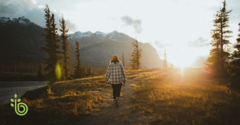 Person walking along a mountain trail at sunrise, symbolizing intentional living, personal growth, and long-term financial goals.