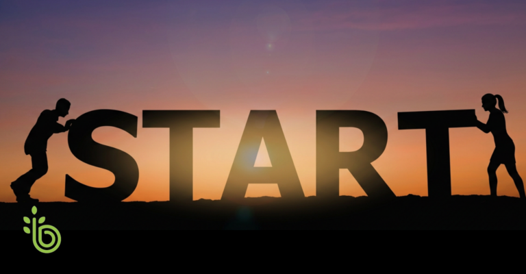 Silhouettes of two people pushing large letters spelling “START” at sunrise, representing the beginning of a financial learning journey.