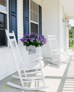 Two white rocking chairs on a peaceful front porch, representing rest, reflection, and creating a life that feels like home after a major life transition.