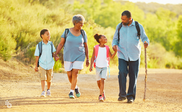 Grandparents hiking with their grandchildren on a sunny trail, representing retirement focused on family, health, and meaningful experiences beyond financial wealth.